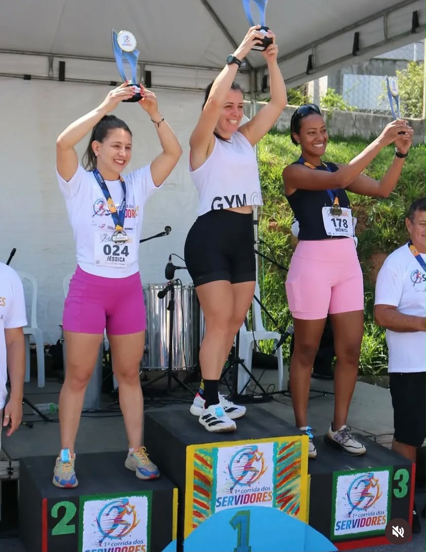 Pódio feminino com as vencedoras erguendo os troféus