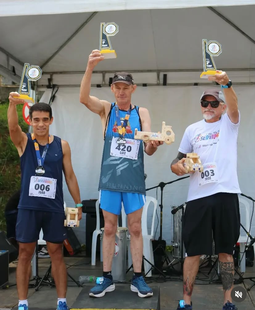 Pódio masculino erguendo troféus e brindes de madeira