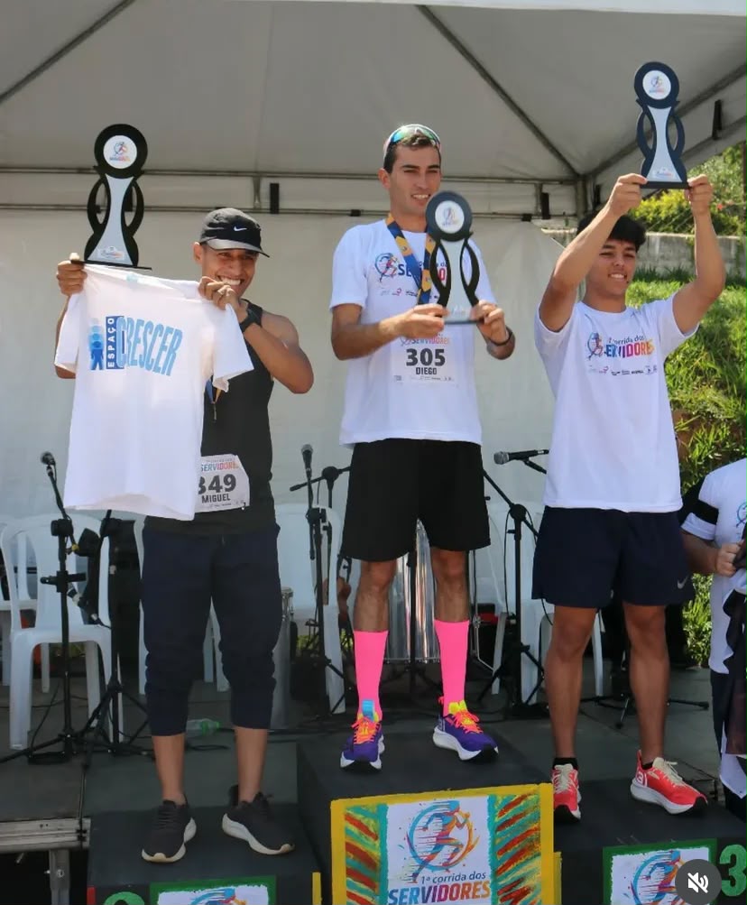 Atletas comemorando no pódio com troféus erguidos