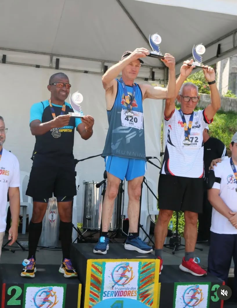Atletas veteranos erguendo troféus no pódio