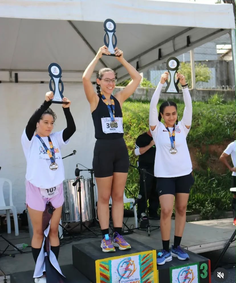 Pódio feminino erguendo troféus da 1ª Corrida dos Servidores