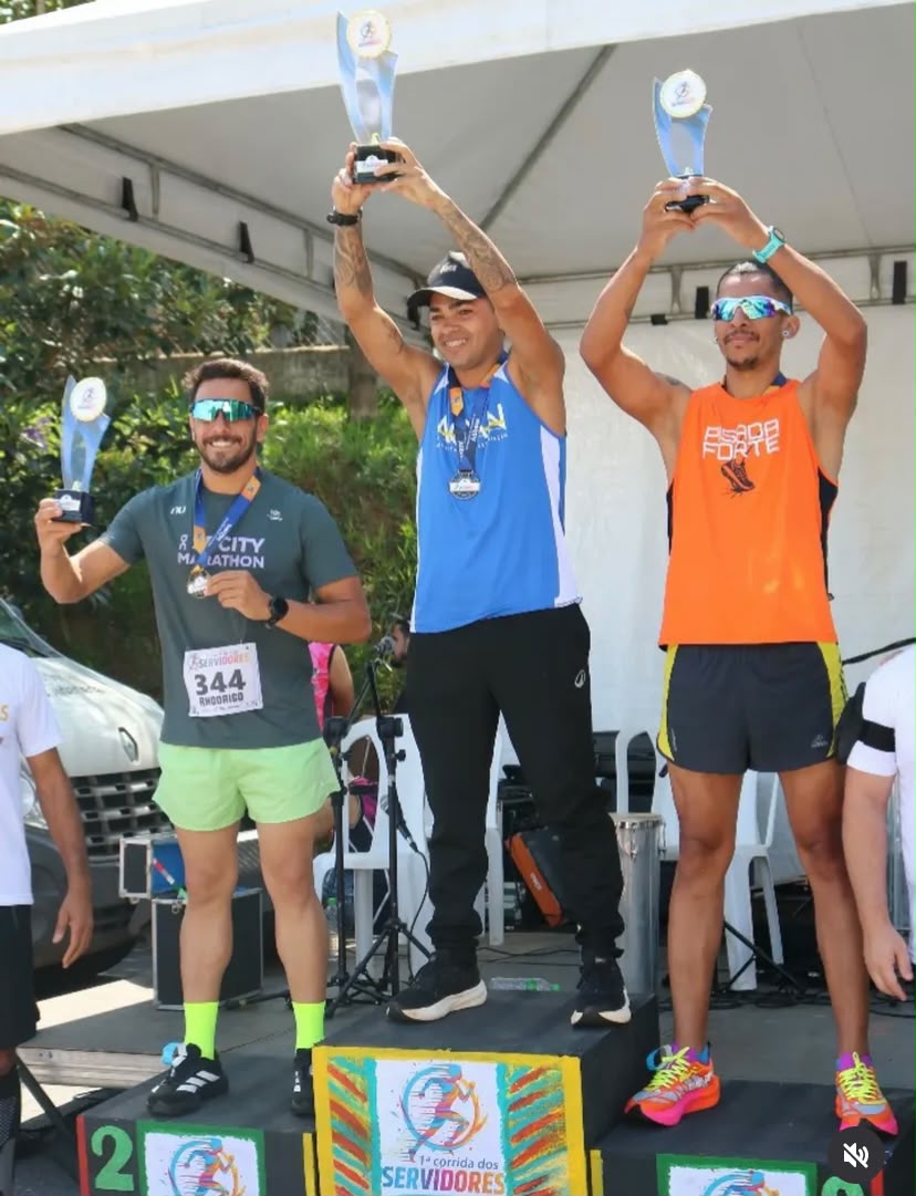 Vencedores masculinos erguendo os troféus no pódio